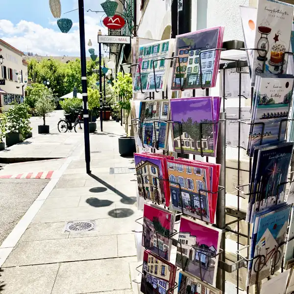 Façades de maisons colorées dans le Vieux Carouge, des arbres au fond et un ciel rose magenta, illustration en couleurs, par Christiane Zimmermann, alias Mamzelle Zimmie.